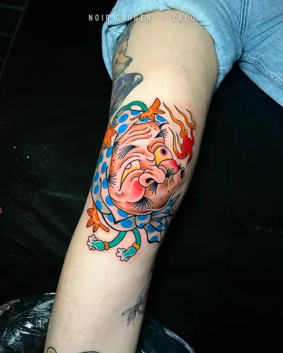 Máscara hyottoko con llama en el brazo