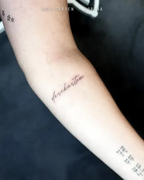 Frase en letra manuscrita de línea fina en el antebrazo