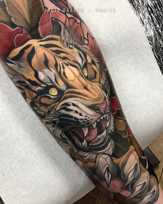 Tigre rugiendo entre peonías en el antebrazo
