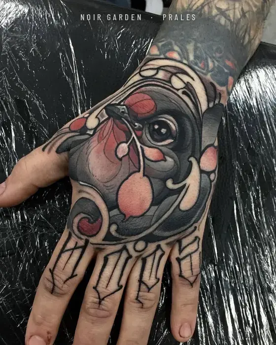 Pájaro y frutos rojos en el dorso de la mano